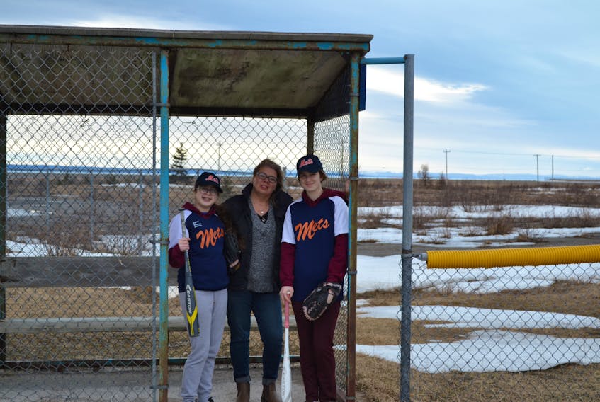 The Chisletts of Stephenville are dedicated to baseball, including from left: Devaro, mom Bernadette and Shilo seen posing for a photo here at a dugout at one of the softball diamonds in Stephenville.