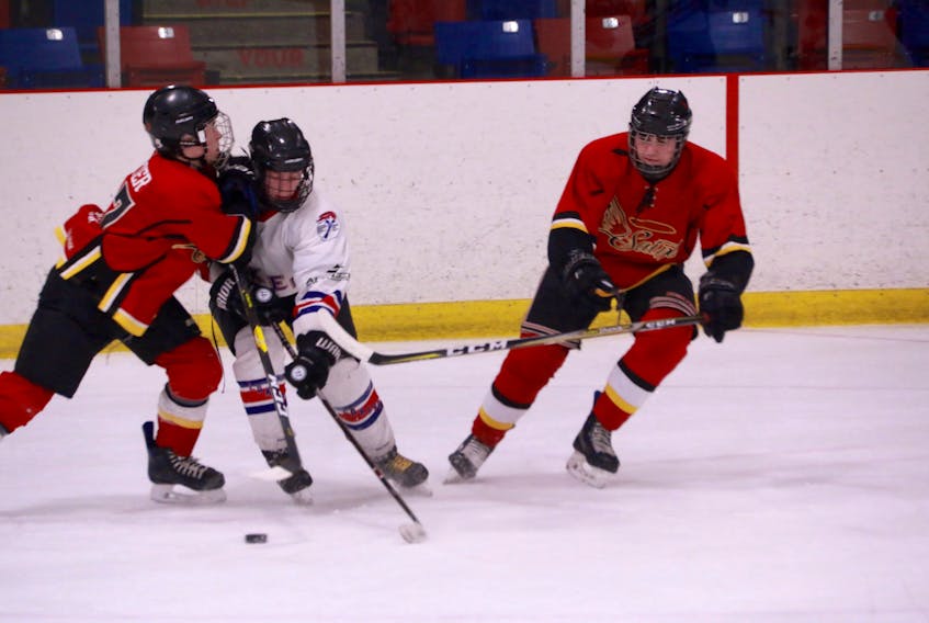 Elwood High Lakers’ Joshua Shears, centre, skates past St. James Regional High Saints players Alexander Carter and Cameron Hann during Game 1 of the West Coast High School Hockey League semifinal series Wednesday at the Hodder Memorial Recreation Complex.