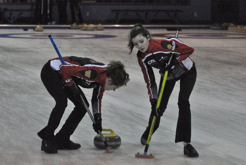 Team Mitchell’s Ainsleigh Piercey, left, and Mikayla O’Reilly sweep a rock released by Sarah McNeil Lamswood during play against Team Follett of St. John’s on Thursday night at the Corner Brook Curling Club.