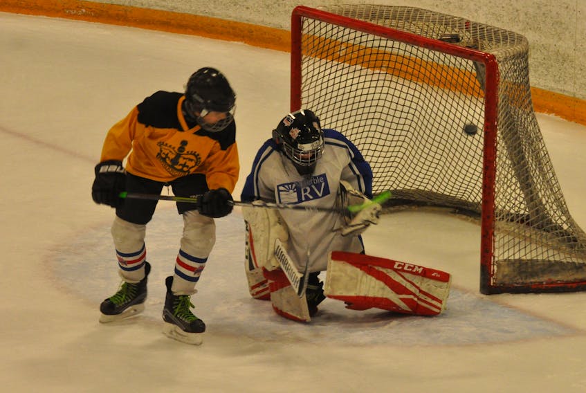 Brady Cave, left, deflects a puck up and over goaltender Jaykob Stone during peewee house league practice at the Kinsmen Arena II on Wednesday as Minor Hockey Week rolls on.