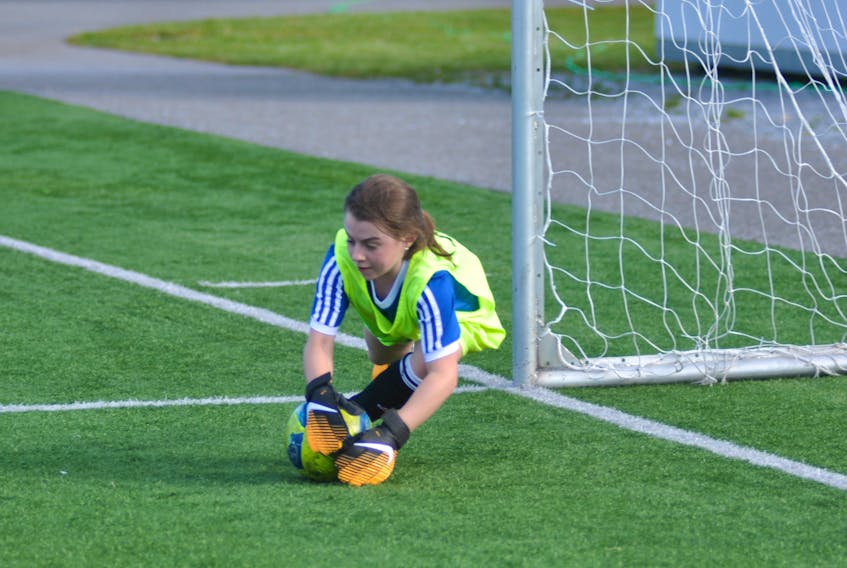 Corner Brook (Blue) goalkeeper Kate Lombard dives to get her hands on a ball directed towards her net by a Mount Pearl (Andrews) striker during Corner Brook Girls Under-10 Soccer Summer Kickoff Tournament play Thursday at Wellington Street Sports Complex.