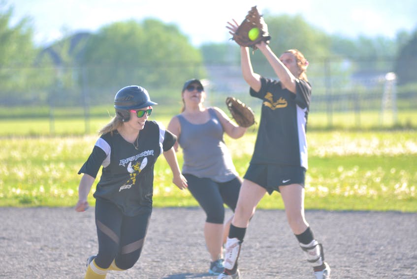 Rapid Power Sports Bees' Rebecca Goulding, left, hustles back to first base to avoid a tag after West Side Monarchs' Rose Ryan catches a pop fly during women's softball league action Wednesday evening at Ambrose O'Reilly Memorial Field.