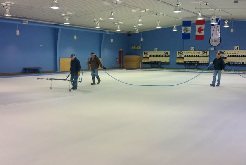 Corner Brook Curling Club member George King is seen spray painting the ice while club members Bern Lewis and Bruce Penney, right, hold the hose while getting the ice ready at the club Tuesday afternoon.