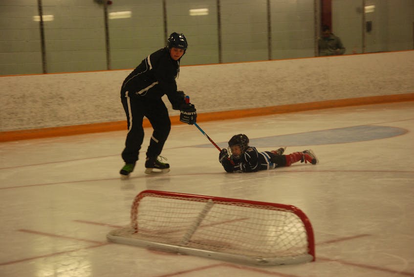 Coach Jana Sigurdsson drags along her son John along the ice during a drill at the Corner Brook minor hockey Timbits 1 practice Saturday morning at the Kinsmen Arena II in Corner Brook.