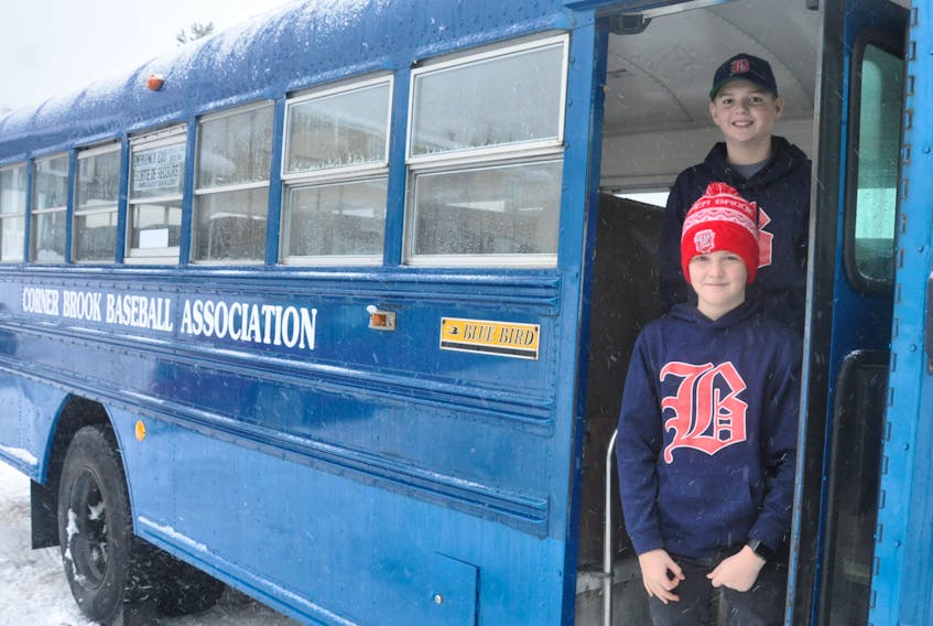 Jacob and Luke Mercer pose in front of the Blue Baron. Ron Mercer, father of the two minor baseball players, hopes to have the Blue Baron back on the road and transporting players to tournaments like it did for decades in the city.