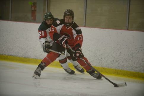 Western Kings defenceman Brady Parsons, right, looks for a teammate while being hounded by Kensington Wild forward Landon Clow Friday at the Atlantic major midget hockey championship in Charlottetown, P.E.I.