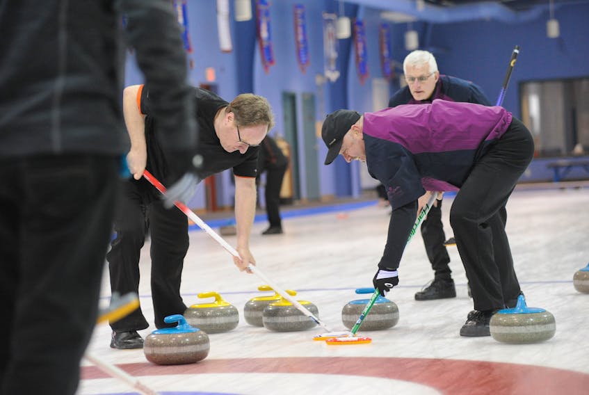 Lead Dennis Bruce, left, and third Mike Mullins, of the Gary Oke rink sweep with all they’ve got to bring along the shot from second Blair Fradsham, seen looking on here, in the Corner Brook foursome’s game against the Baxter House rink of Gander in sixth-end action from the provincial senior men’s curling championship at the Corner Brook Curling Club Saturday.