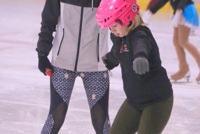 After completing her own practice time, senior skater Emma Canning, left, volunteers, as do all the senior skaters, to stay later into the day to help coach younger skaters like Isabelle Langdon, who spent time working on her skating edges.