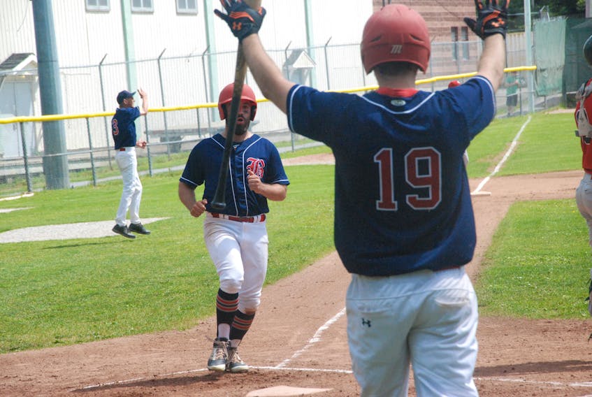 Aaron Flood is greeted with the stop sign by Travis Taylor at home plate after scoring the first run of the opening game of the provincial senior A baseball final against the St. John's Capitals Saturday at Jubilee Field in Corner Brook. The Barons won the opener 5-4 in eight innings with A.J. Whiffen socking a solo walkoff homer.