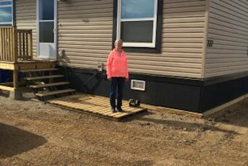 ['Judy Hoots stands near the entrance to her and husband Mike’s new home in Fort McMurray..']
