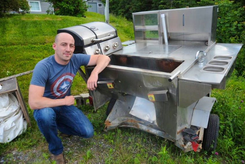 D.J. Pike of Mount Moriah poses for a photo next to his extensively damaged food cart, which he hopes to replace so he can get back in business.