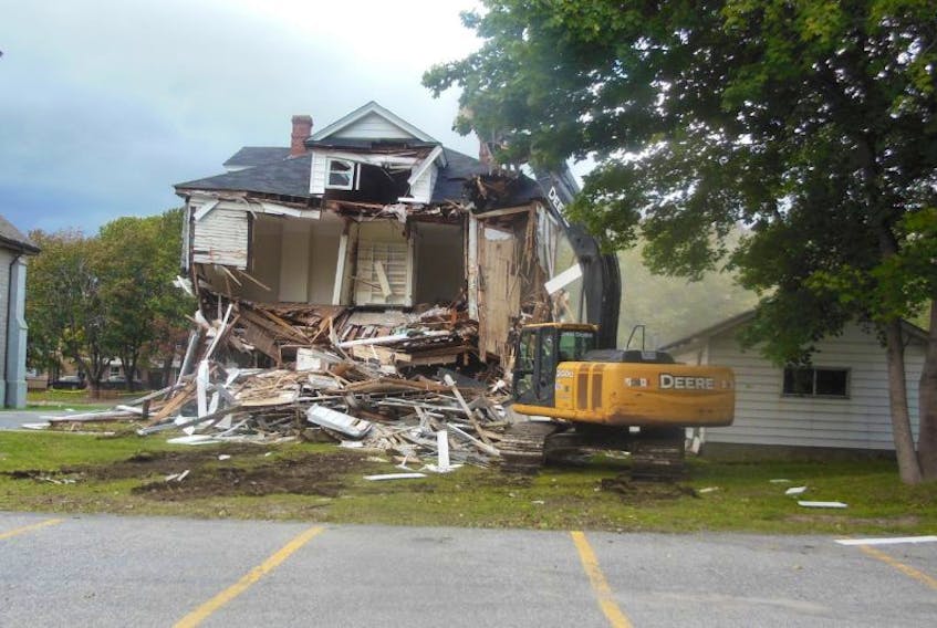 An excavator goes to work taking down the First United Church manse on Park Street in Corner Brook Sunday.