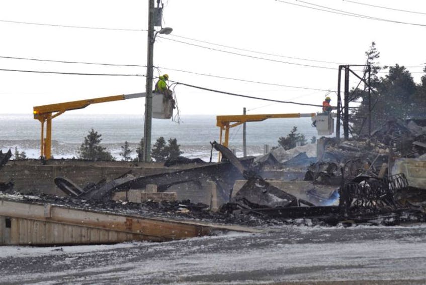 With rubble from Abbott & Haliburton Home Hardware Centre seen in front of them, technicians with Bell Aliant were still replacing wires on Tuesday that were burned off during the early Monday morning fire.