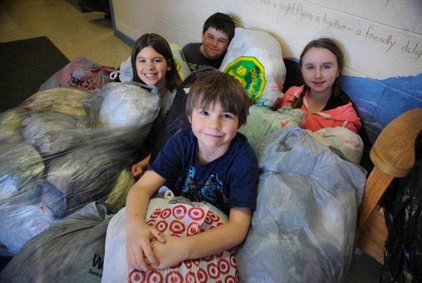 Ewan Jenkins, front, and his Grade 3 classmates, from left, Keira Parrill, Rhys Cormier and Izabelle Jones sit amongst a fraction of the plastic shopping bags collected by C.C. Loughlin Elementary as part of the Plastic Bag Grab Challenge they’ve taken on during the month of May.