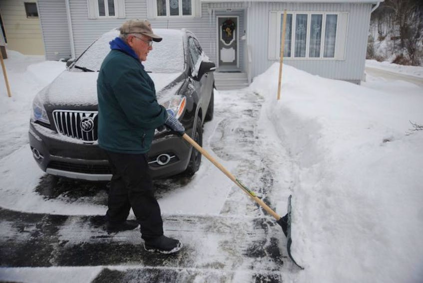 Fred Wall scrapes away the light dusting of snow in his driveway on O’Connell Drive in Corner Brook Friday afternoon in preparation for the big snowfall expected in the region Christmas Eve and Christmas Day.