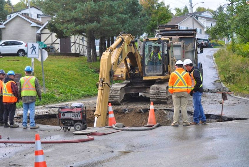Employees with the City of Corner Brook survey the situation as a backhoe continues to dig up the site of a major waterline break on Wellington Street at the intersection with upper Valley Road on Wednesday morning.