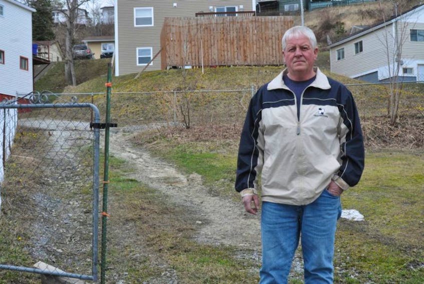 Joe Bennett stands in front of the fence on his Prince Street property that neighbours want removed.