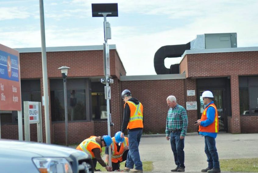 Mayor Tom O’Brien, centre, and Dwayne Russell, right, manager of municipal services with the Town of Stephenville, look on as employees of the Town of Stephenville’s Public Works department put finishing touches on one of the two new crosswalk traffic lights installed at the intersection of Main Street and St. George’s Avenue Extension in Stephenville.