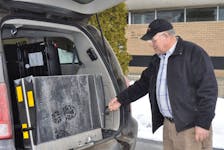 Ivan Pittman, owner of Pittman’s Taxi in Norris Point, reaches out to pull out the wheelchair ramp in his new accessible minivan. Pittman used a $25,000 grant from the province to help pay for the van.