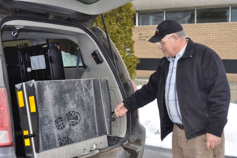 Ivan Pittman, owner of Pittman’s Taxi in Norris Point, reaches out to pull out the wheelchair ramp in his new accessible minivan. Pittman used a $25,000 grant from the province to help pay for the van.