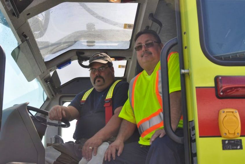 Mark Cooke, left, airport technician and airport rescue firefighter, sits in the cab of one of the Deer Lake Regional Airport’s rescue and firefighting vehicles with maintenance supervisor John Ryan.
