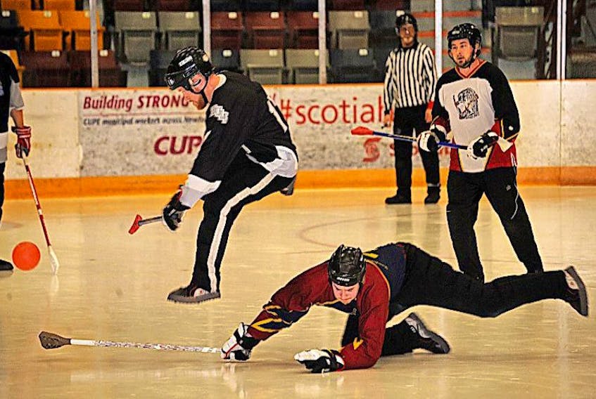 Western Building Products’ Mike Hawco leaps into the air to avoid tripping over a lunging pokecheck by Newfoundland Fasteners’ Scott Wayson in this file photo of men’s broomball league play last season at the Corner Brook Civic Centre.