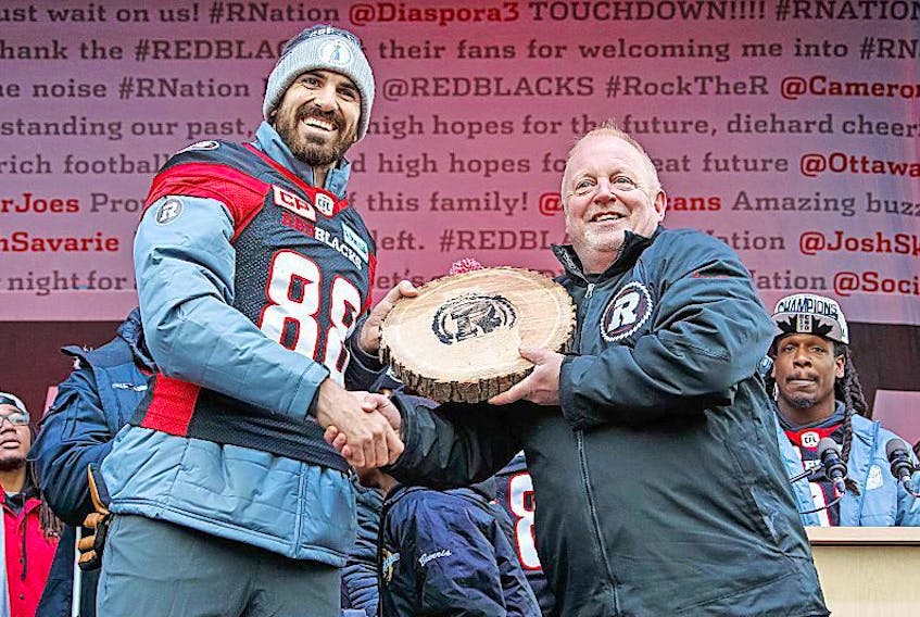 Jeff Hunt, left, presents the Ottawa Redblacks’ symbol of excellence, a “wood cookie” cut by chainsaw from the team’s touchdown log, to player Brad Sinopoli, who scored one of the Grey Cup touchdowns in this file photo.