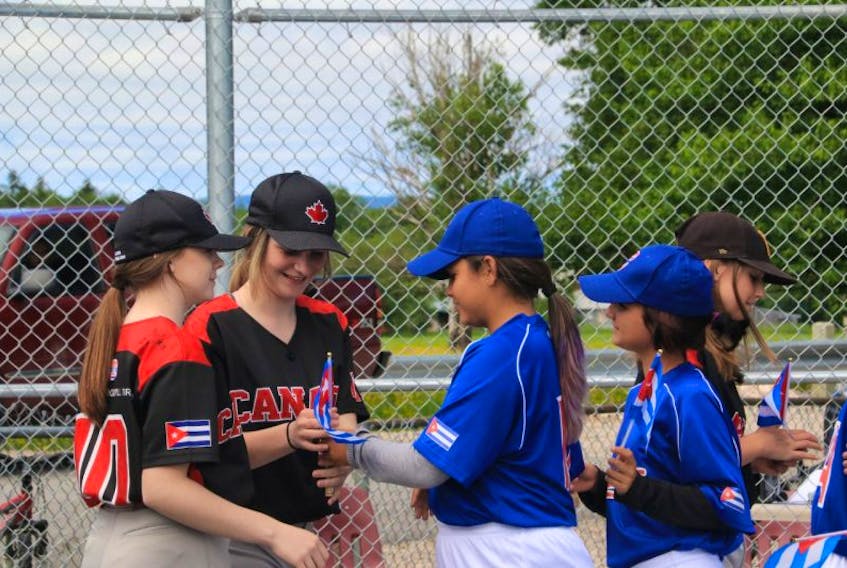 From left, Team Canada (Pasadena) players Emma Hennessey and Bethany Brophy, Team Cuba players Stephany O’Connor and Danet De La Torre, and Team Canada player Victoria Hull happily exchange flags following their baseball game Saturday in Pasadena.