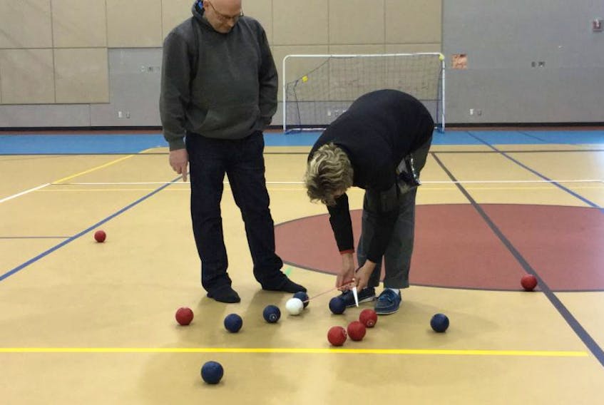 Margaret Tibbo, president of ParaSport NL, demonstrates how the indoor version of boccia is played to participants and parents at an introduction to the sport in late December at the Studio in Corner Brook. Richard Kendell, whose son Steven was at the event, lends a helping hand.