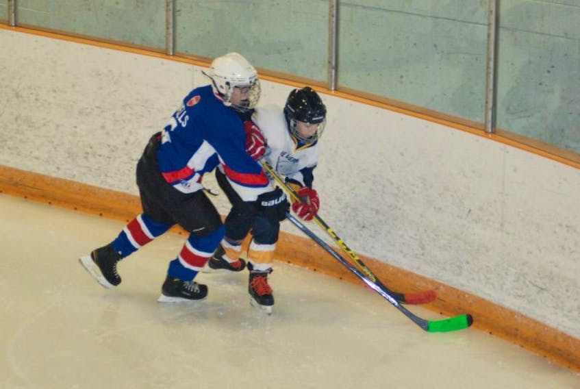 Baie Verte Sabres’ Evan Davis and Corner Brook Royals’ Marcus Wells go for the puck in the corner during the second game of the two-game set on Saturday.