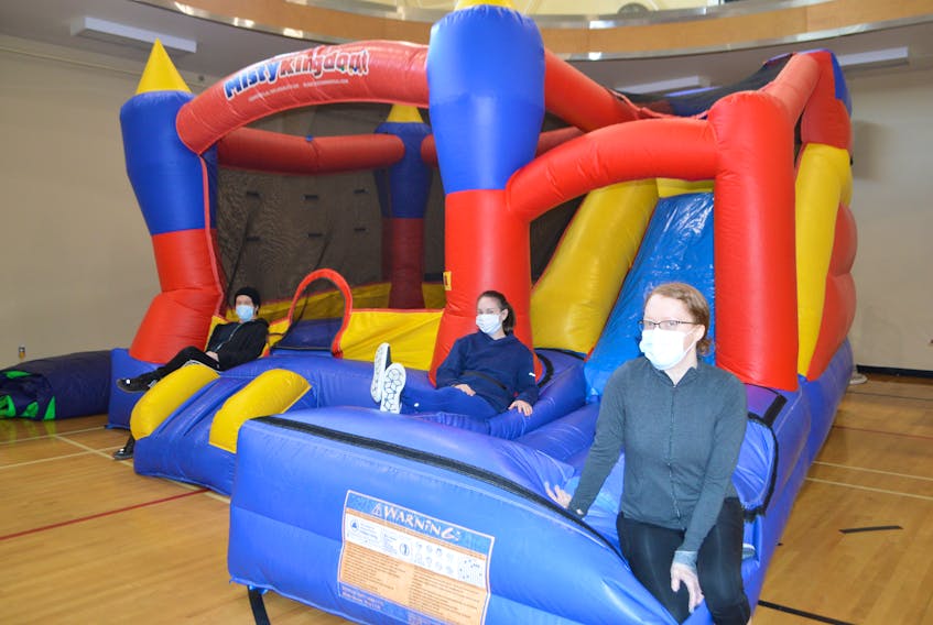 Sheldon Grant, right, of Sydney, personal trainer and wellness coach at the Frank Rudderham Family YMCA in Sydney, Janice Curnew, centre, manager of programs, and Sarah MacPherson, wellness centre team leader, relax on a big bouncy house at the YMCA Thursday, one of the items that will be up for sale during the Spring Sale at the YMCA in Sydney, Saturday from 9 a.m.-12 noon. Officials at the YMCA said they will have items from office equipment to exercise equipment and much more, their way of clearing out and refreshing the bulding before their upcoming reopening. Sharon Montgomery-Dupe/Cape Breton Post