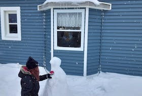A resident watches through her window as Lux Forsey works on a snowman outside the Blue Crest Nursing Home in Grand Bank Wednesday. 
PAUL HERRIDGE/THE TELEGRAM
