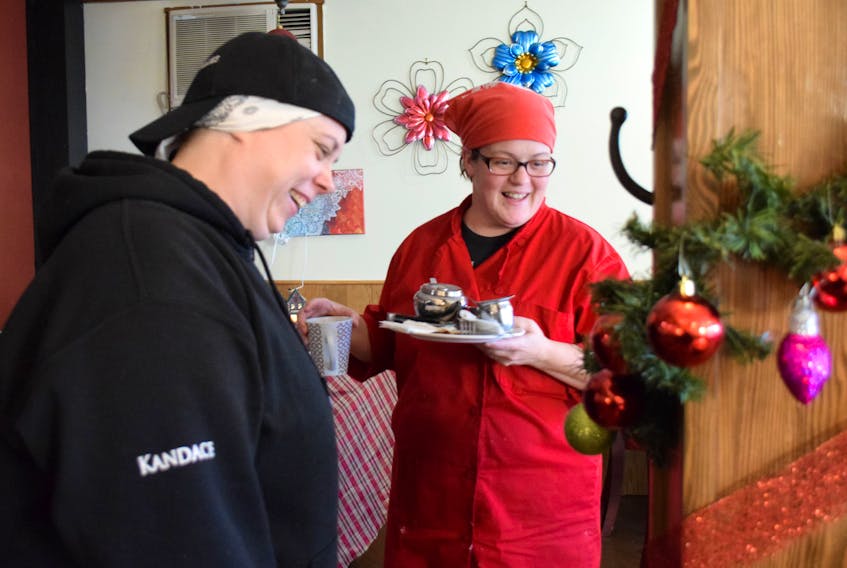 Kandace Asprey (left) and Megan Egan smile at one of the sentiments written on an ornament adorning   their Shelburne café, Nova Scotia Rollies and Catering Company.
