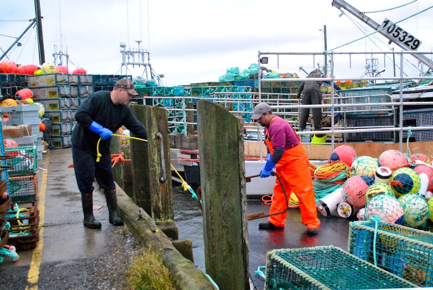 Fishermen load their boats with lobster fishing gear on Nov. 25 at the Lower Woods Harbour wharf on what was supposed to be dumping day for LFA 33 and 34.  Weather caused a one-day delay in the season opening. KATHY JOHNSON PHOTO