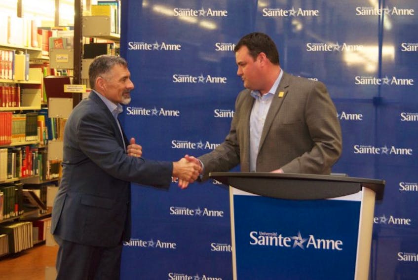 West Nova MP Colin Fraser and Sainte-Anne president and vice-chancellor Allister Surette shake hands as $440,000 in federal funding is announced for the university’s library.