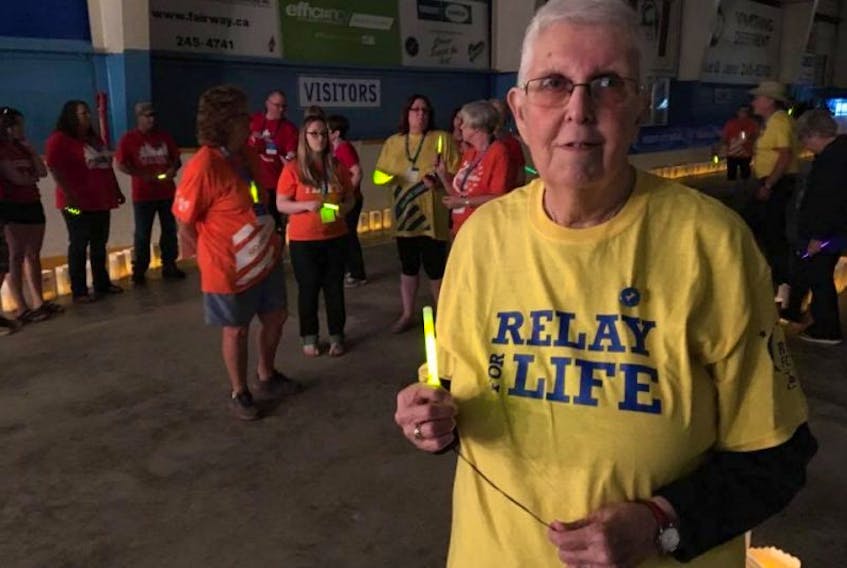 ['The night’s ambassador Jean Brittain lights up her glow stick for the luminary lap, which is walked in silence to honour those who’ve fought and are fighting cancer.']