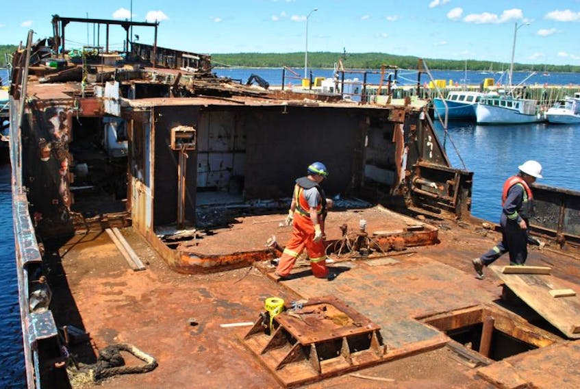 Workers with Clean Earth Technologies walk across the deck of the MV Farley Mowat during an initial assessment of the vessel derelict July 6.