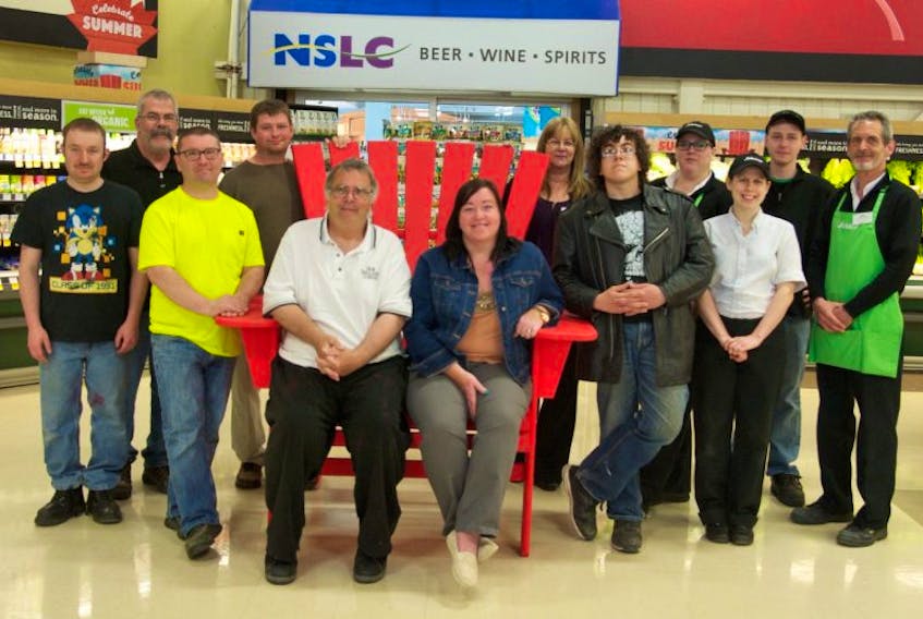 In no particular order: Dave Weir, George MacDonald, Stephen Savary, Stephen Sharp, Gordon Wilson, Shane Mullen, Melanie Singleton, Wendy LeBlanc and several Sobeys employees stand with the new chair built by clients at Conway Workshop.