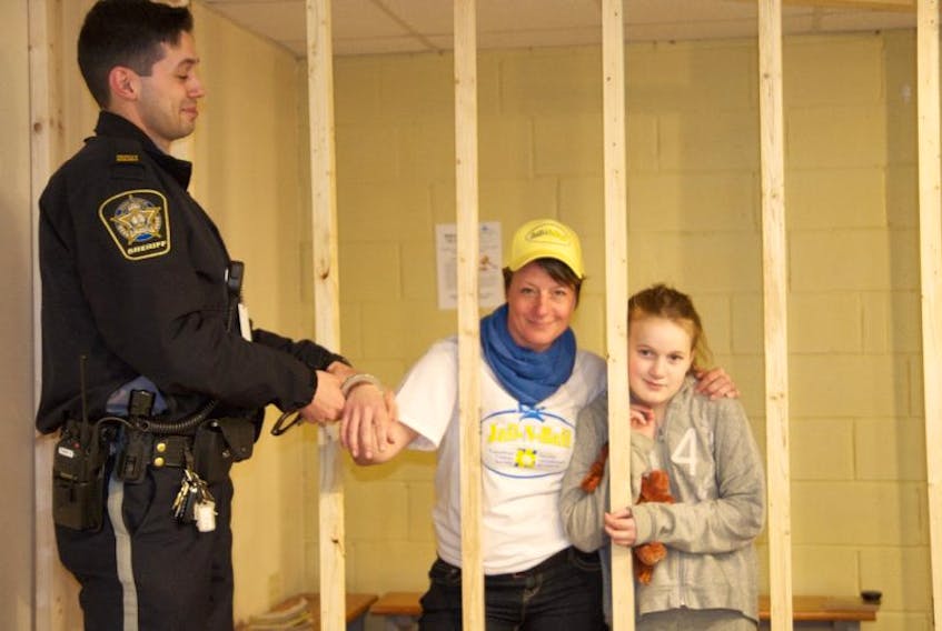 Dawn Thomas, Senior Safety Coordinator at the Digby RCMP stands with Megan Estabrooks in the holding cell as Nick Murphy of Sherriff Services cuffs her at the event. Everyone who was arrested was a good sport and the event was a success, according to organizer Niki Lewis.