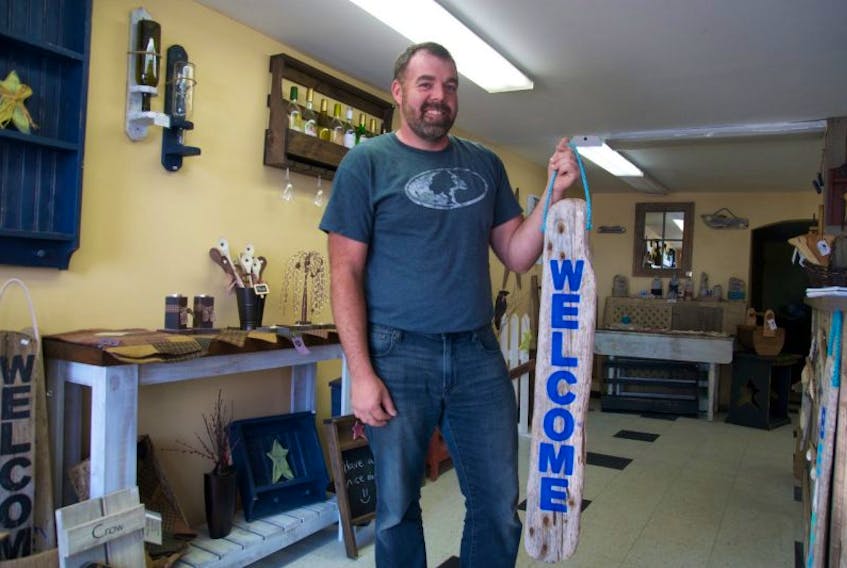 Robert Warner stands with a welcome sign of his own design at his new store called the Wood Shop, located at 47 Water Street in Digby.